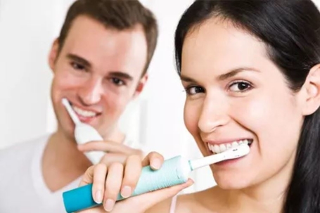 man and woman brushing their teeth